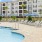 a pool with chairs and umbrellas by a building